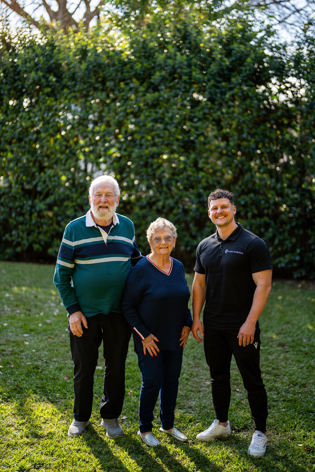 Older couple standing in their garden with a Healthproof clinician