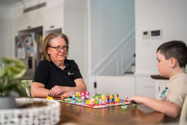 Healthproof occupational therapist playing a board game with a boy at home