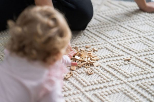 Toddler playing with wooden blocks on a rug during a home therapy session