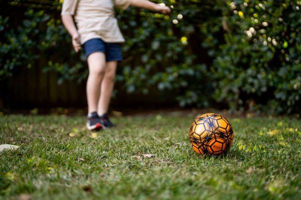 Child kicking a soccer ball in a backyard