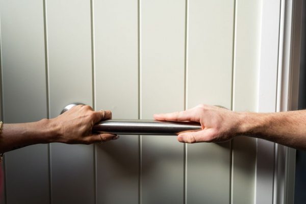 Hands fitting a grab rail to a wall during a home safety assessment