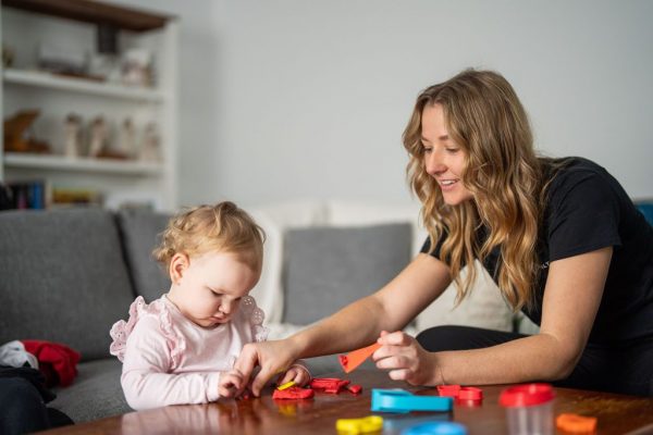 Healthproof speech pathologist playing with a toddler on the floor
