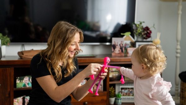 Healthproof speech pathologist using a toy with a toddler during therapy