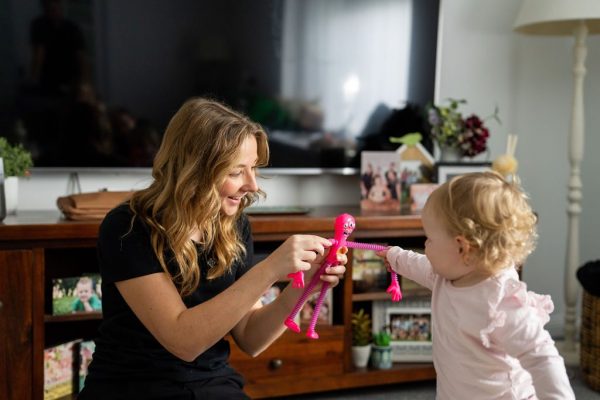 Healthproof speech pathologist using a toy with a toddler during therapy