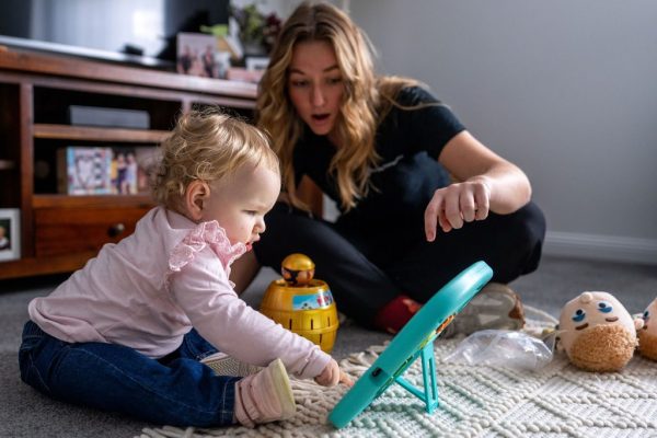 Healthproof speech pathologist and a toddler playing with therapy toys on a rug