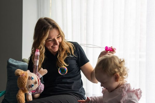 Healthproof speech pathologist sitting on the floor with a young client