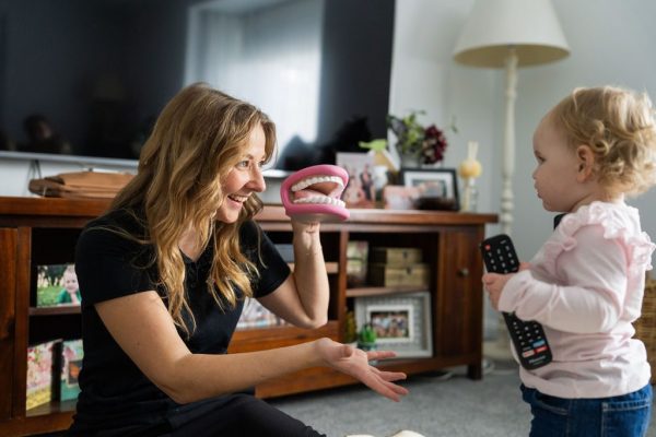 Healthproof speech pathologist using a dental model to demonstrate to a child